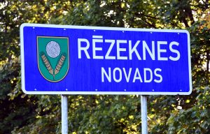 Zila informatīvā ceļa zīme ar uzrakstu "Rēzeknes novads" un novada ģerboni.