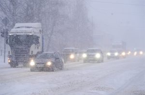 Intensīva snigšana un satiksme uz pilsētas ielas ziemas putenī