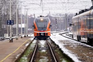 Oranžs pasažieru vilciens dzelzceļa stacijā ziemā