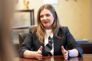 Sieviete intervijas laikā skaidro savu viedokli pie galda