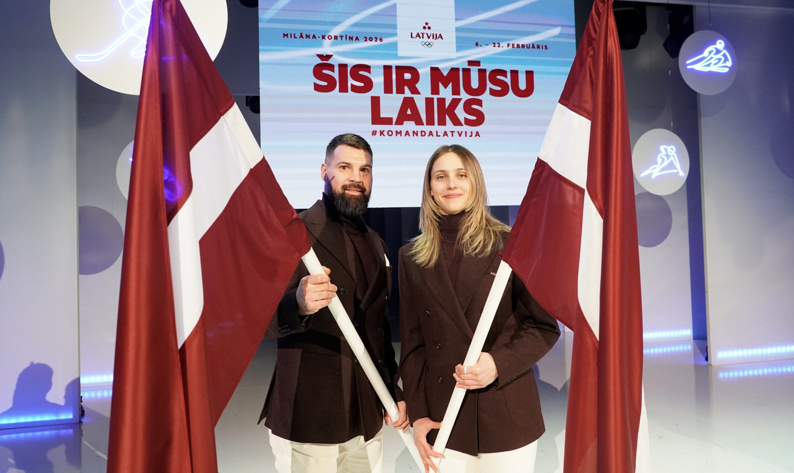 Latvijas olimpiskās delegācijas karognesēji ar Latvijas karogiem Milāna–Kortina 2026 pasākumā