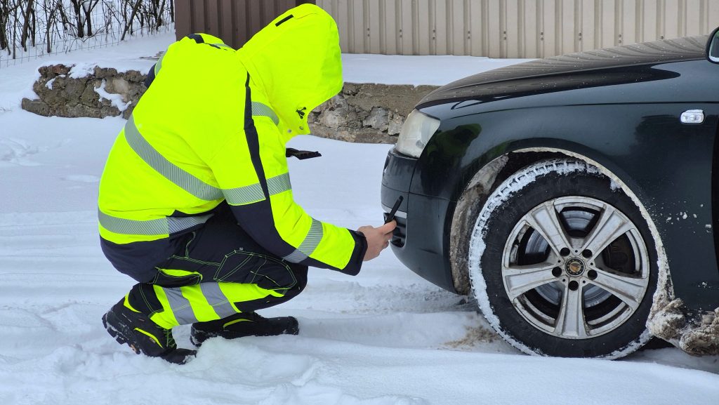 CSDD darbinieks ar speciālu mērierīci pārbauda vieglās automašīnas riepas protektora dziļumu.