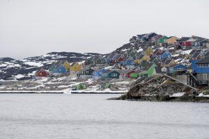 Krāsainas koka mājas kalnainā piekrastē Āsiātas pilsētā Grenlandē ziemas sezonā