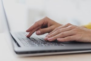 Sievietes rokas, kas strādā ar portatīvā datora tastatūru