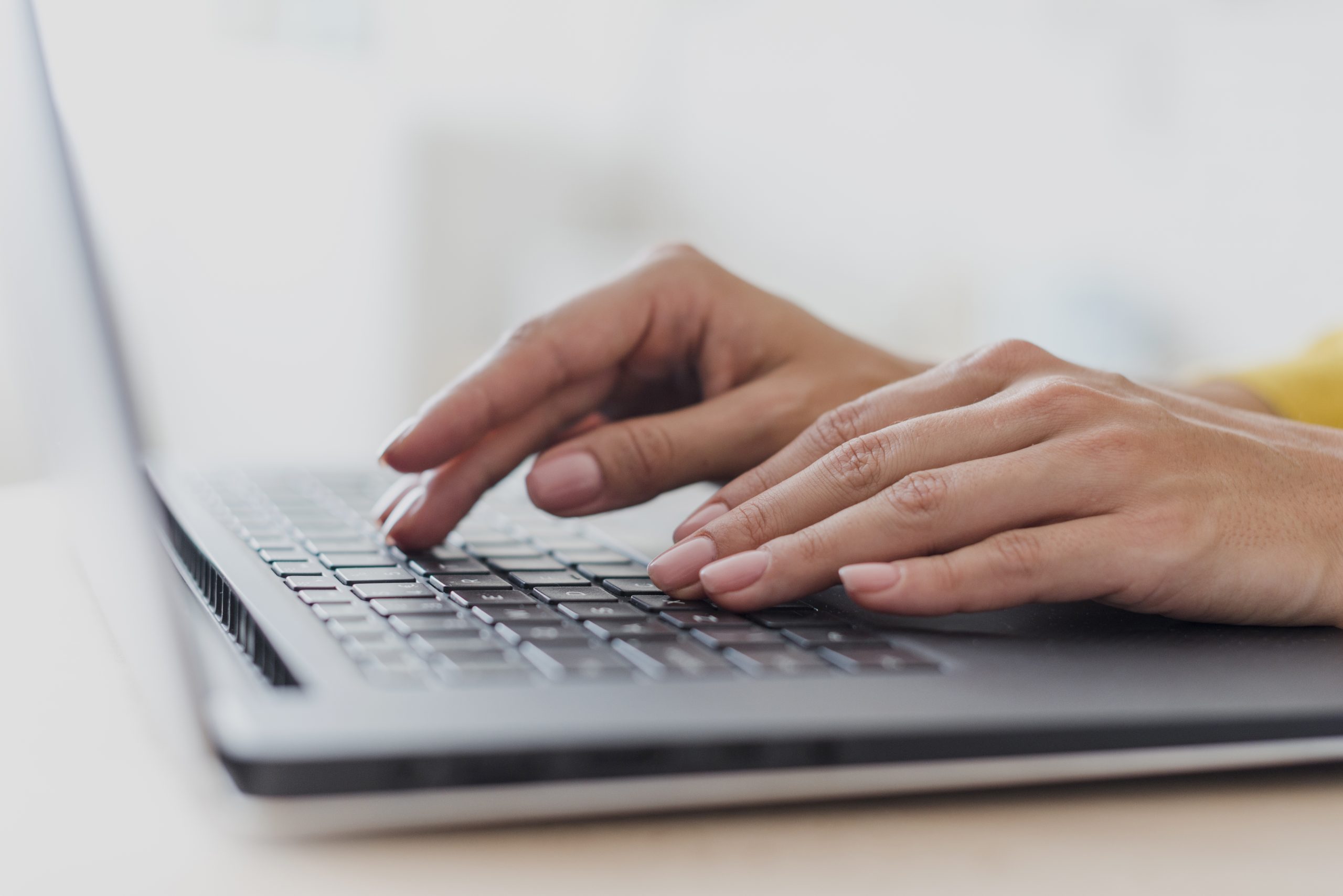 Sievietes rokas, kas strādā ar portatīvā datora tastatūru