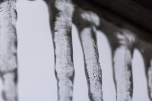 Tuvplāns ar garām lāstekām, kas karājas no ēkas jumta malas.