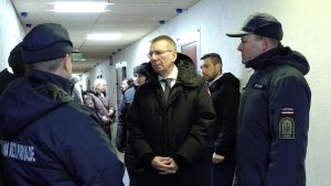 Valsts prezidents Edgars Rinkēvičs tumšā mētelī sarunājas ar Ieslodzījuma vietu pārvaldes darbiniekiem cietuma gaitenī.