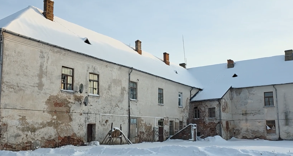 Ilūkstes jezuītu klostera pagalma puse ziemā ar sniegu klātu jumtu un vairākiem skursteņiem.