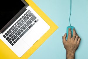Dators un pele uz darba galda kā simbols klikšķu ēsmai un manipulējošiem virsrakstiem internetā