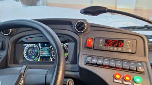 Elektroautobusa vadītāja kabīne ziemā – redzams digitālais panelis, klimata kontrole un apsnidzis logs fonā.