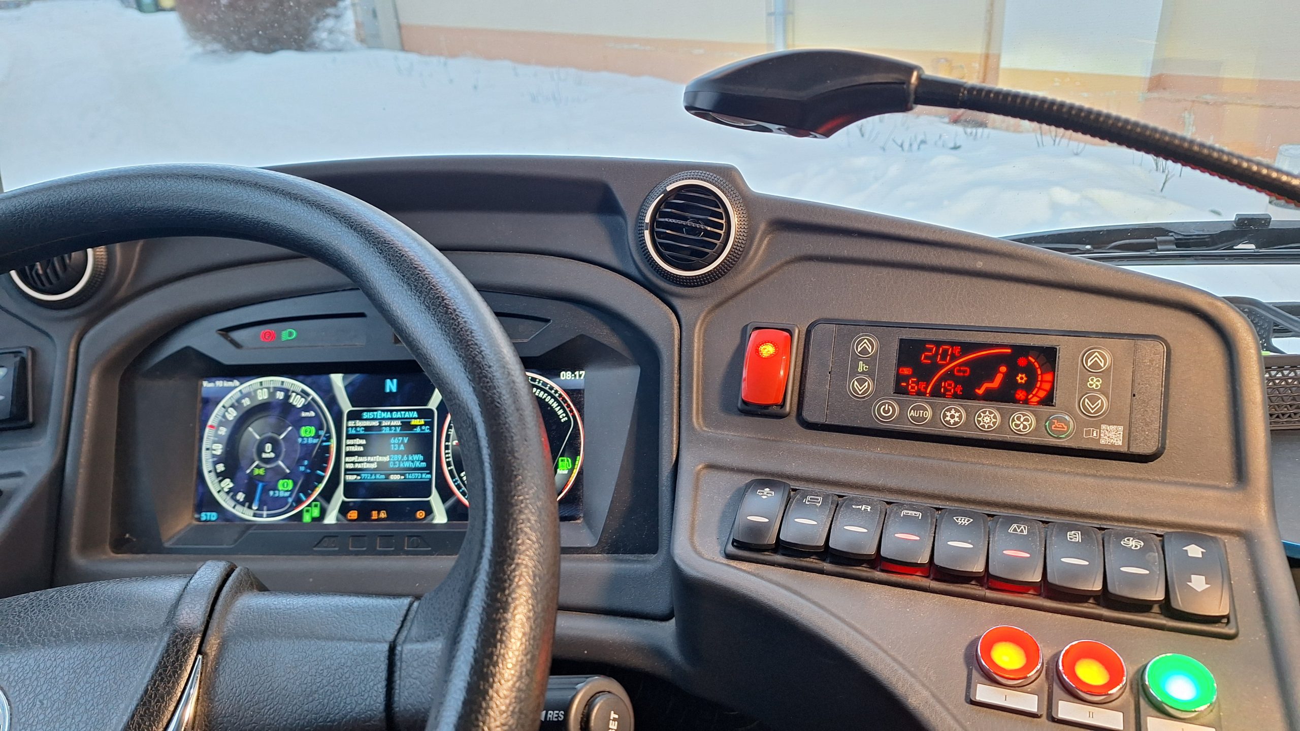 Elektroautobusa vadītāja kabīne ziemā – redzams digitālais panelis, klimata kontrole un apsnidzis logs fonā.