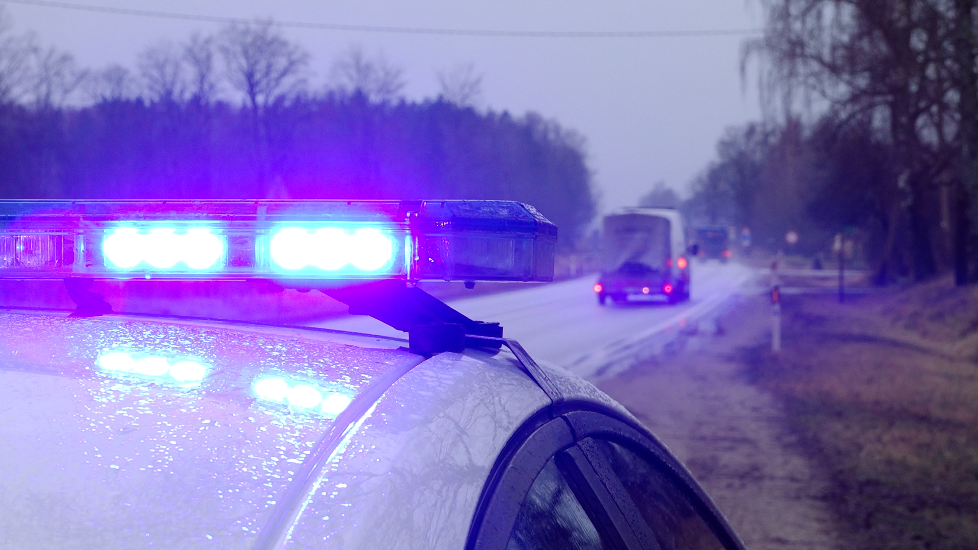 Operatīvā dienesta transportlīdzeklis ar ieslēgtām zilajām bākugunīm uz ceļa ārpus apdzīvotas vietas.