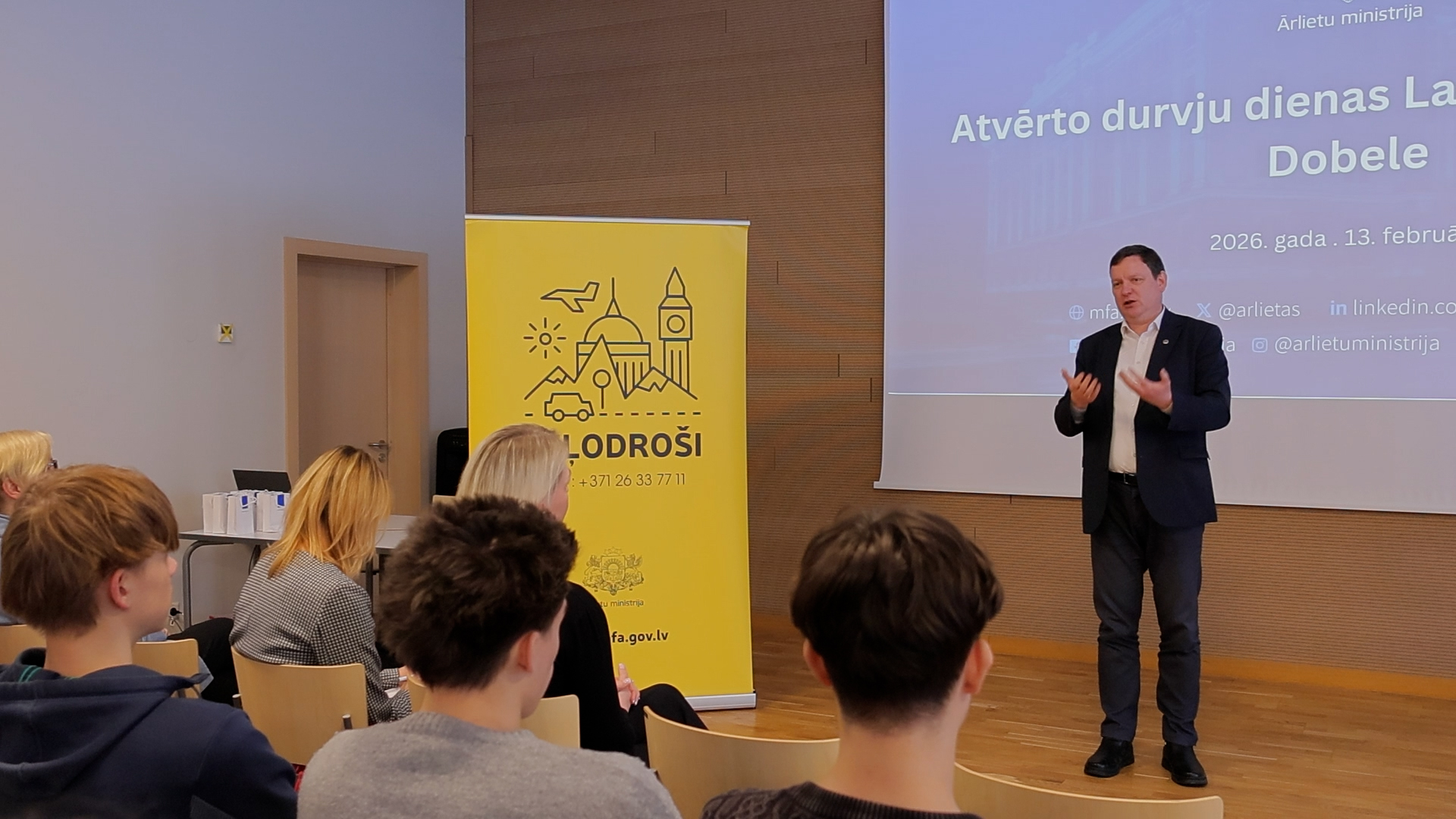 Ārlietu ministrijas pārstāvis uzstājas Dobeles Valsts ģimnāzijā atvērto durvju dienā jauniešu auditorijas priekšā.