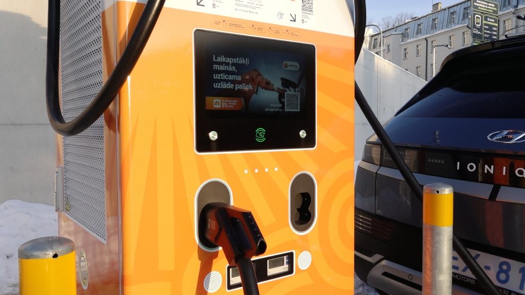 Elektroauto uzlādes stacija ar digitālu ekrānu un pievienotu automašīnu