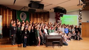 Ekoskolu Ziemas forums Jelgavā – jaunieši un pedagogi pulcējušies uz skatuves ar “Eco-Schools” karogu fonā.