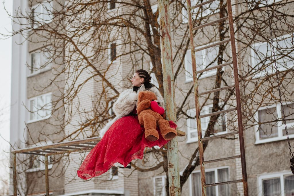 Evika Muizniece fotosesijā ar rotaļu lāci ziemas vidē.