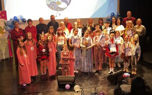 Konkursa dalībnieki un organizatori kopbildē uz skatuves ar diplomiem.