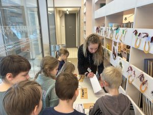 Bērni piedalās izglītojošā nodarbībā par drošu interneta lietošanu bibliotēkā kopā ar bibliotekāri.