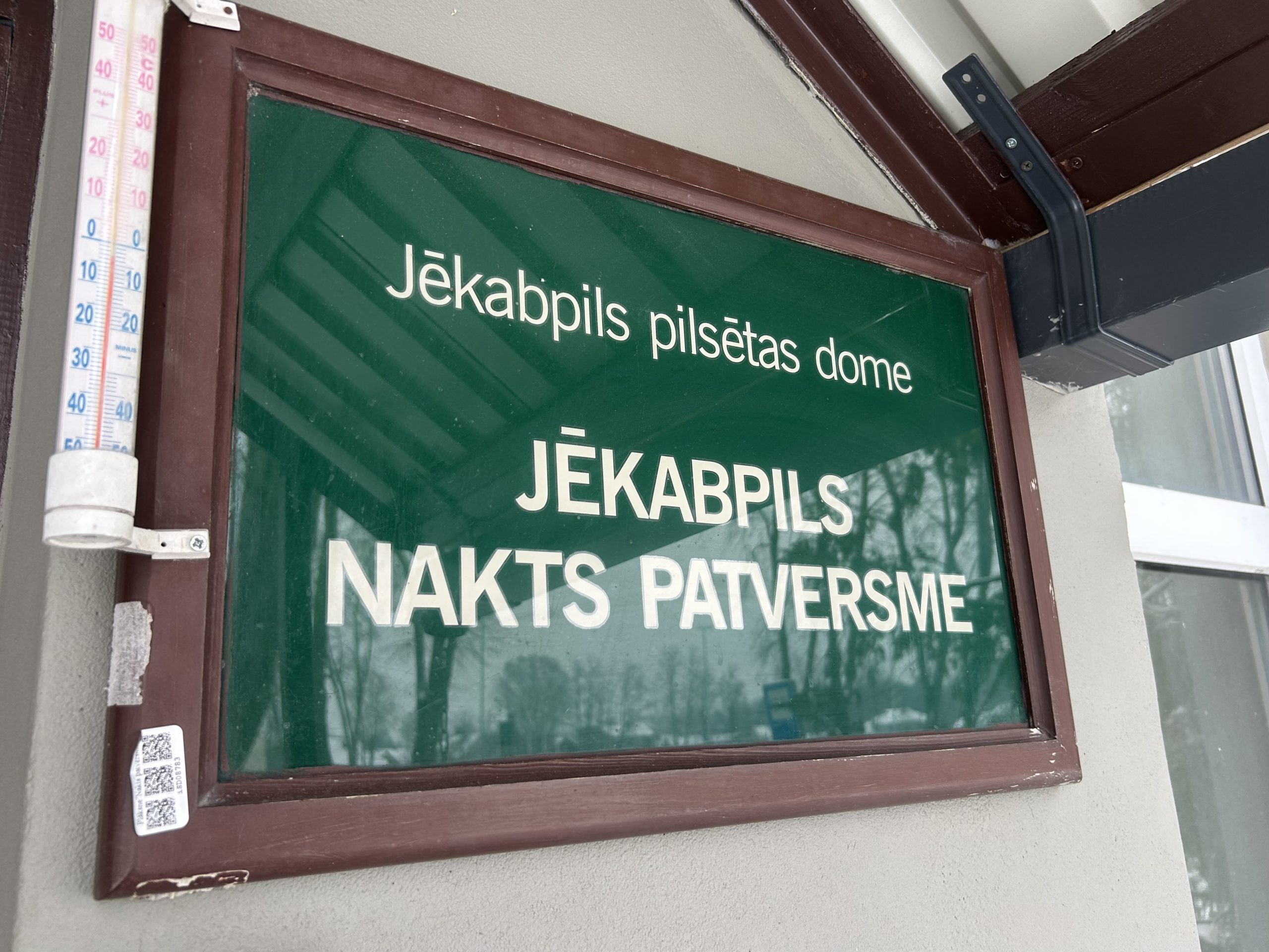 Jēkabpils Nakts patversmes izkārtne pie ēkas ieejas ziemas laikā.