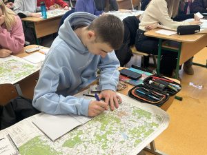 Skolēns klasē strādā ar topogrāfisko karti, atzīmējot objektus ģeogrāfijas stundā.