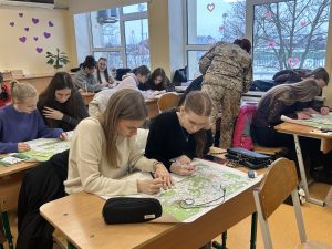 Skolēni klasē strādā ar kartēm, veicot uzdevumus ģeogrāfijas stundā.