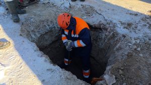 “Jelgavas ūdens” darbinieks veic remontdarbus tranšejā ziemas apstākļos