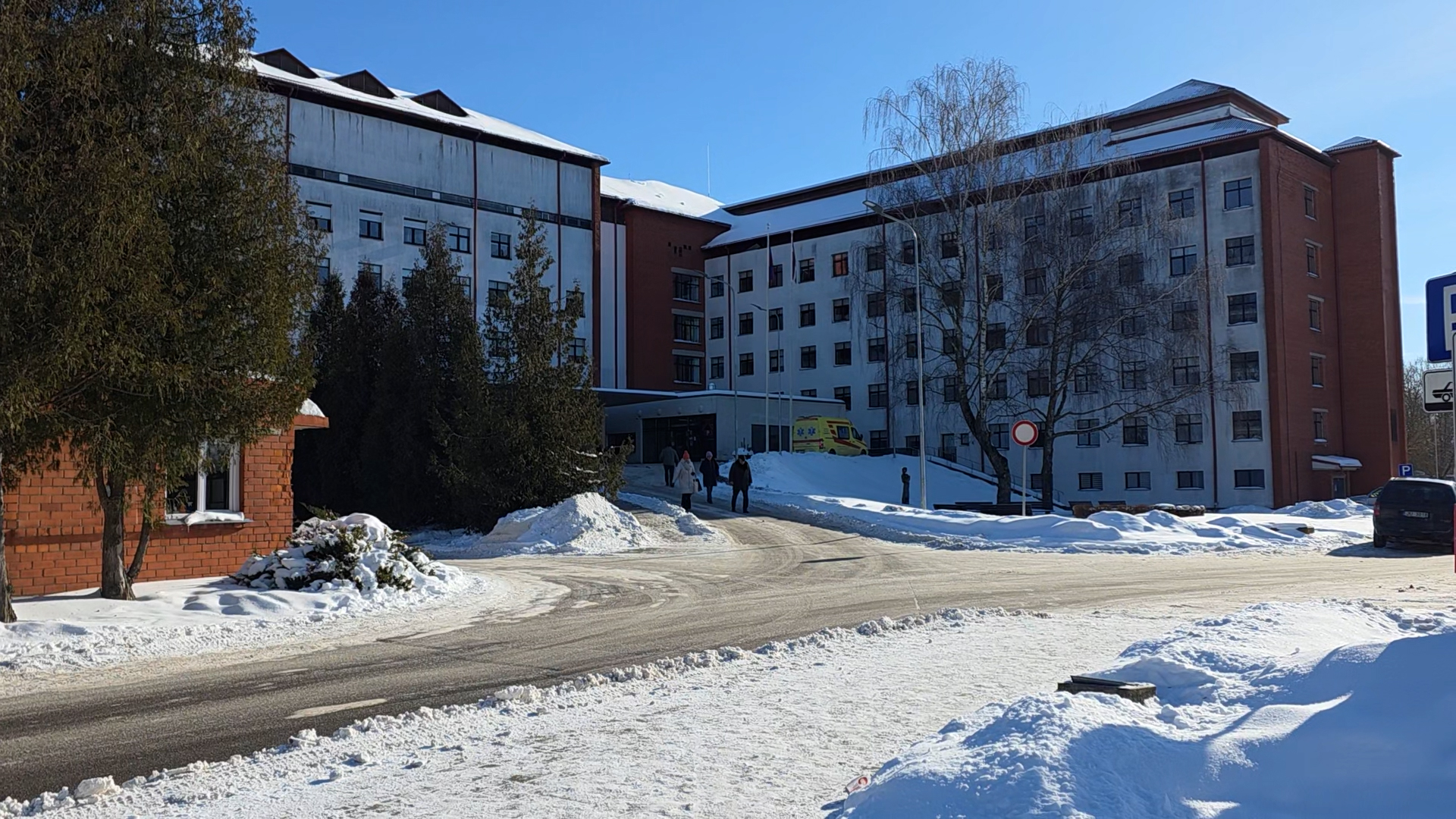 Jelgavas pilsētas slimnīcas ēka ziemā ar piebraucamo ceļu un neatliekamās palīdzības automašīnu.