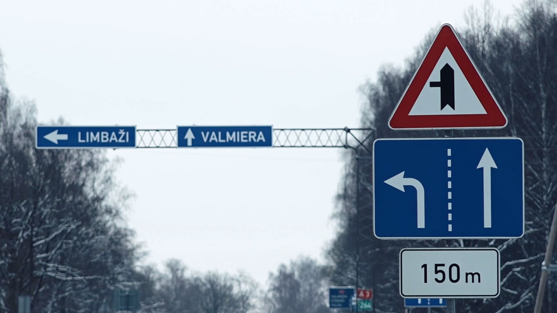 Ceļa zīmes ar norādēm uz Limbažiem un Valmieru ziemas apstākļos, krustojums pēc 150 metriem.
