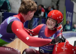 Latvijas kamaniņu sportisti komandu stafetē Milānas un Kortīnas olimpiskajās spēlēs 2026 – Elīna Ieva Bota un komandas biedrs pēc finiša.