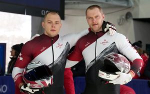 Latvijas bobslejisti Jēkabs Kalenda un Matīss Miknis ar ķiverēm olimpiskajās spēlēs