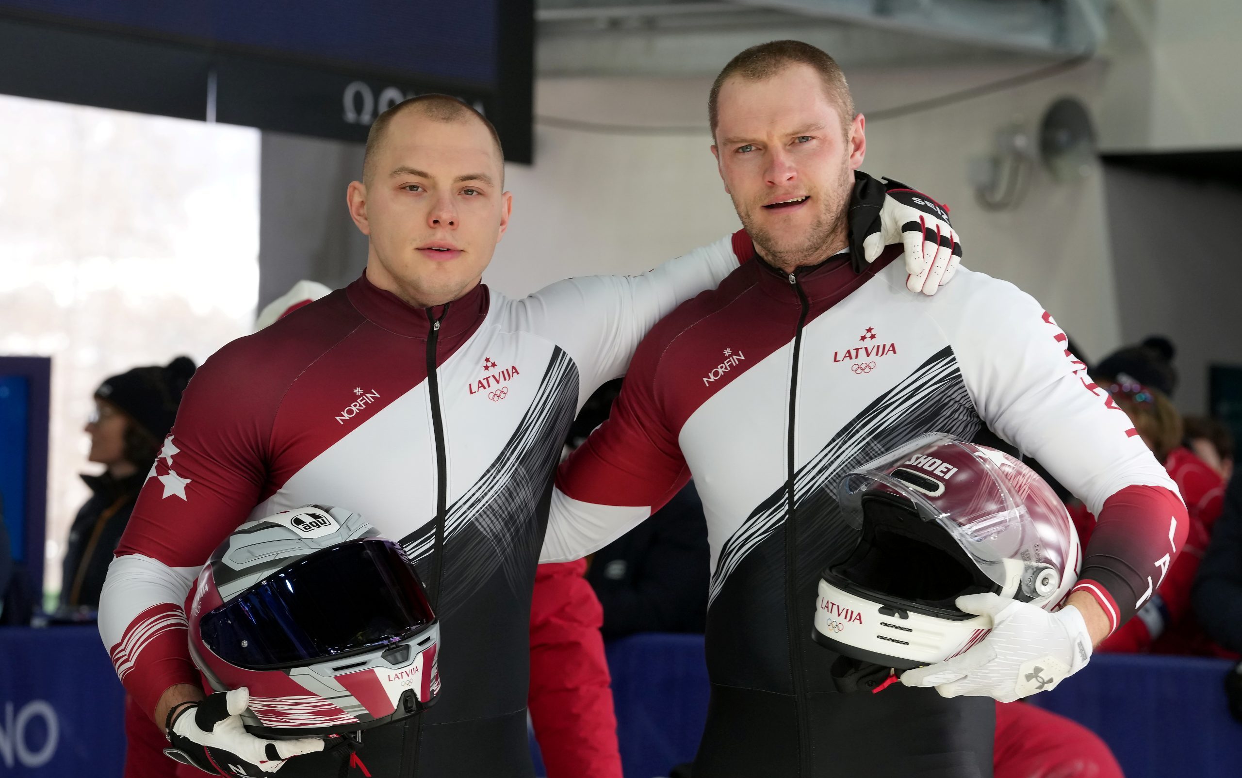 Latvijas bobslejisti Jēkabs Kalenda un Matīss Miknis ar ķiverēm olimpiskajās spēlēs
