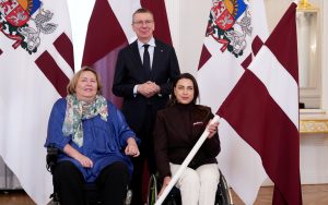 Valsts prezidents Edgars Rinkēvičs kopā ar divām parasportistēm pie Latvijas karogiem oficiālā tikšanās reizē.