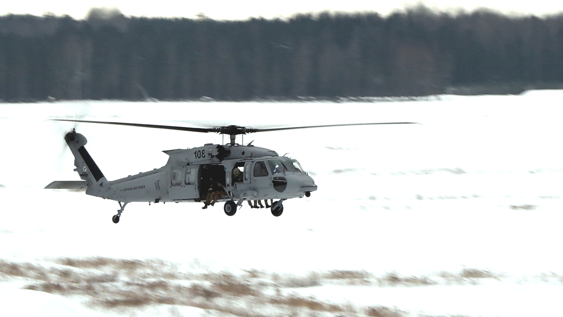 Latvijas Gaisa spēku helikopters mācību laikā Sēlijas militārajā poligonā, ziemas apstākļos nolaižot karavīrus kaujas šaušanas zonā.