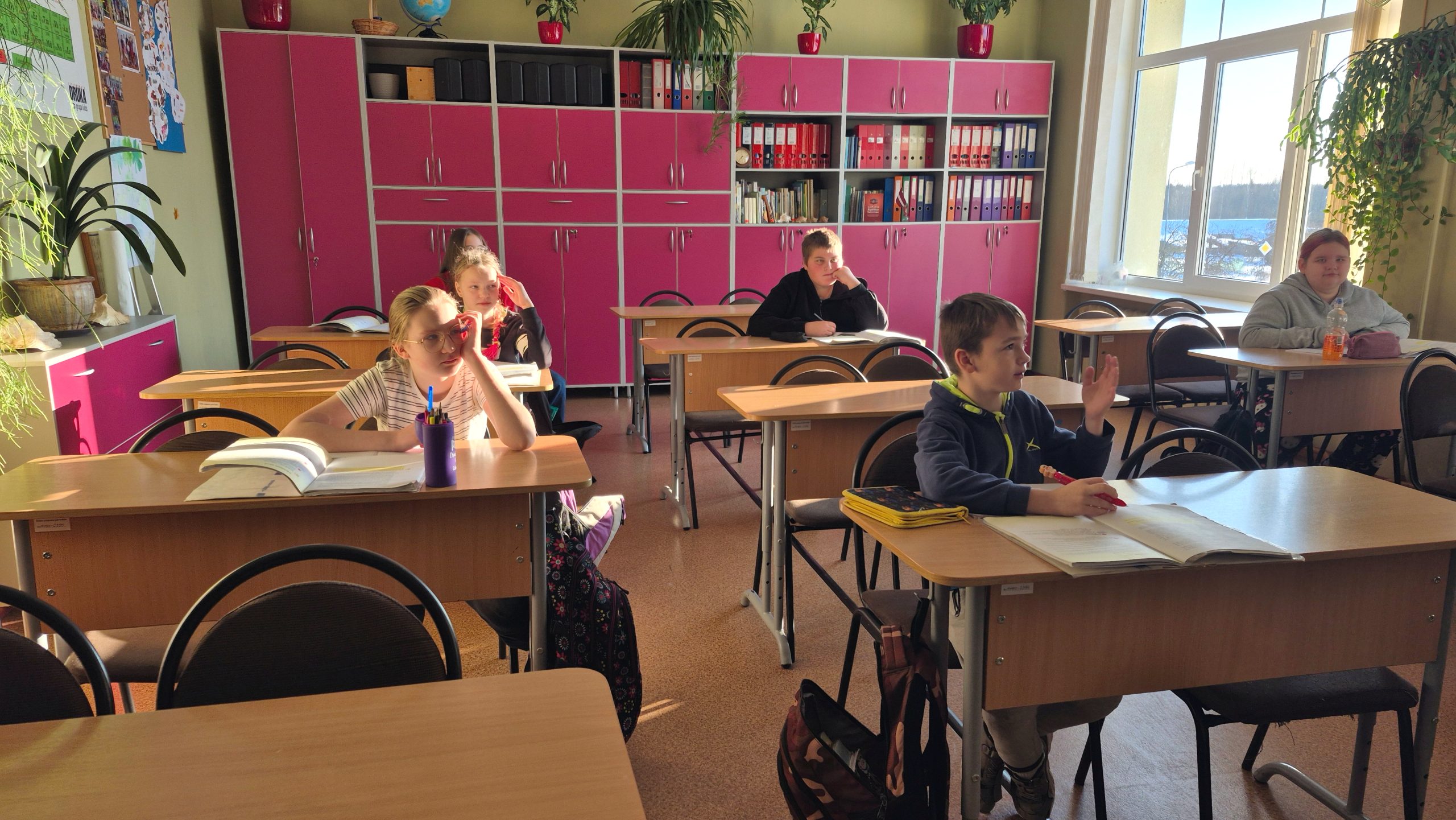 Skolēni Sūnu pamatskolas klasē pie skolas soliņiem sala laikā.