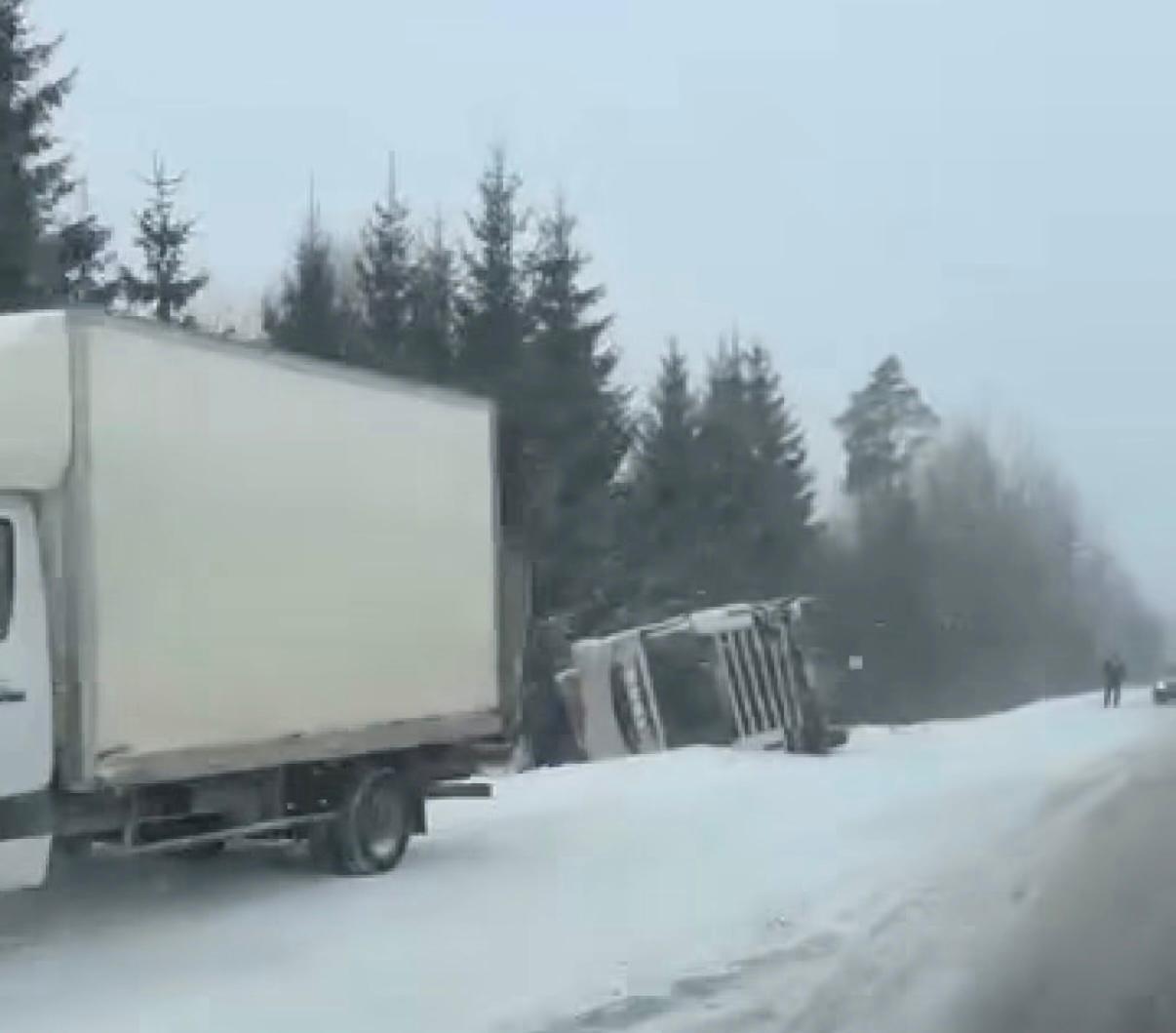 Kravas automašīna apgāzusies uz sāniem sniegotā ceļā meža tuvumā.