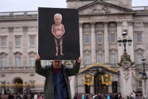 Vīrietis ar plakātu pie Bekingemas pils Londonā