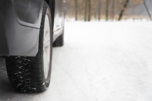 Automašīnas riepa uz sniegota ceļa ziemas apstākļos.