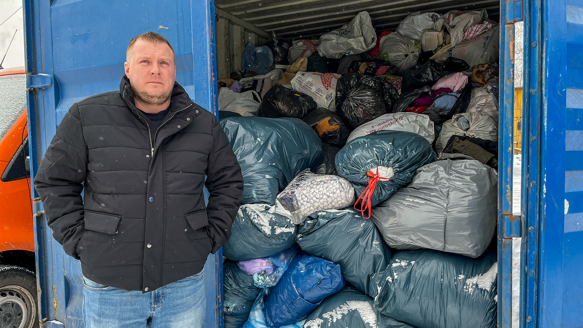 Jānis Ezerkalns stāv pie konteinera ar tekstila maisiem Kuldīgā