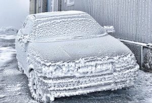 Ar biezu sarmu klāts vieglais automobilis pie ēkas stiprā salā