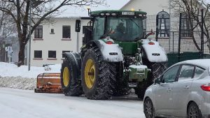 Traktors ar sniega tīrīšanas aprīkojumu izved sniegu no pilsētas ielas ziemas laikā.