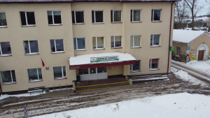 Priekules slimnīcas ēka ziemā ar galveno ieeju un uzrakstu “Priekules slimnīca” virs durvīm.