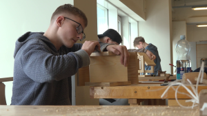 Skolēni apstrādā koka detaļu darbnīcā