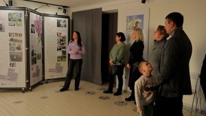 Grupa cilvēku Dobeles Dārzkopības institūtā pie informatīva stenda "Ziedu ceļos" pasākuma atklāšanā.