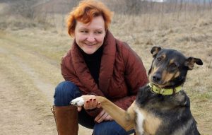 Iveta Skudra ārā dabā kopā ar suni, paspiežot tam ķepu.