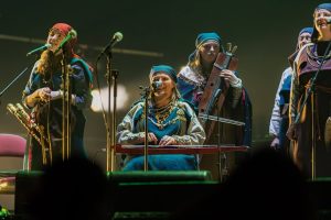 Folkloras grupa tradicionālos tērpos uzstājas uz skatuves.
