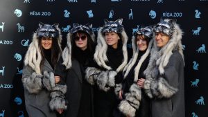 Cilvēki vilku maskās pasākumā pie Rīgas Zooloģiskā dārza sienas