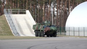 Militārais bruņutransportieris pārvietojas poligonā pie testēšanas rampas