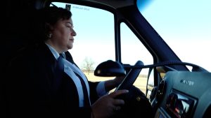 Sieviete pie autobusa stūres vada transportlīdzekli darba laikā.