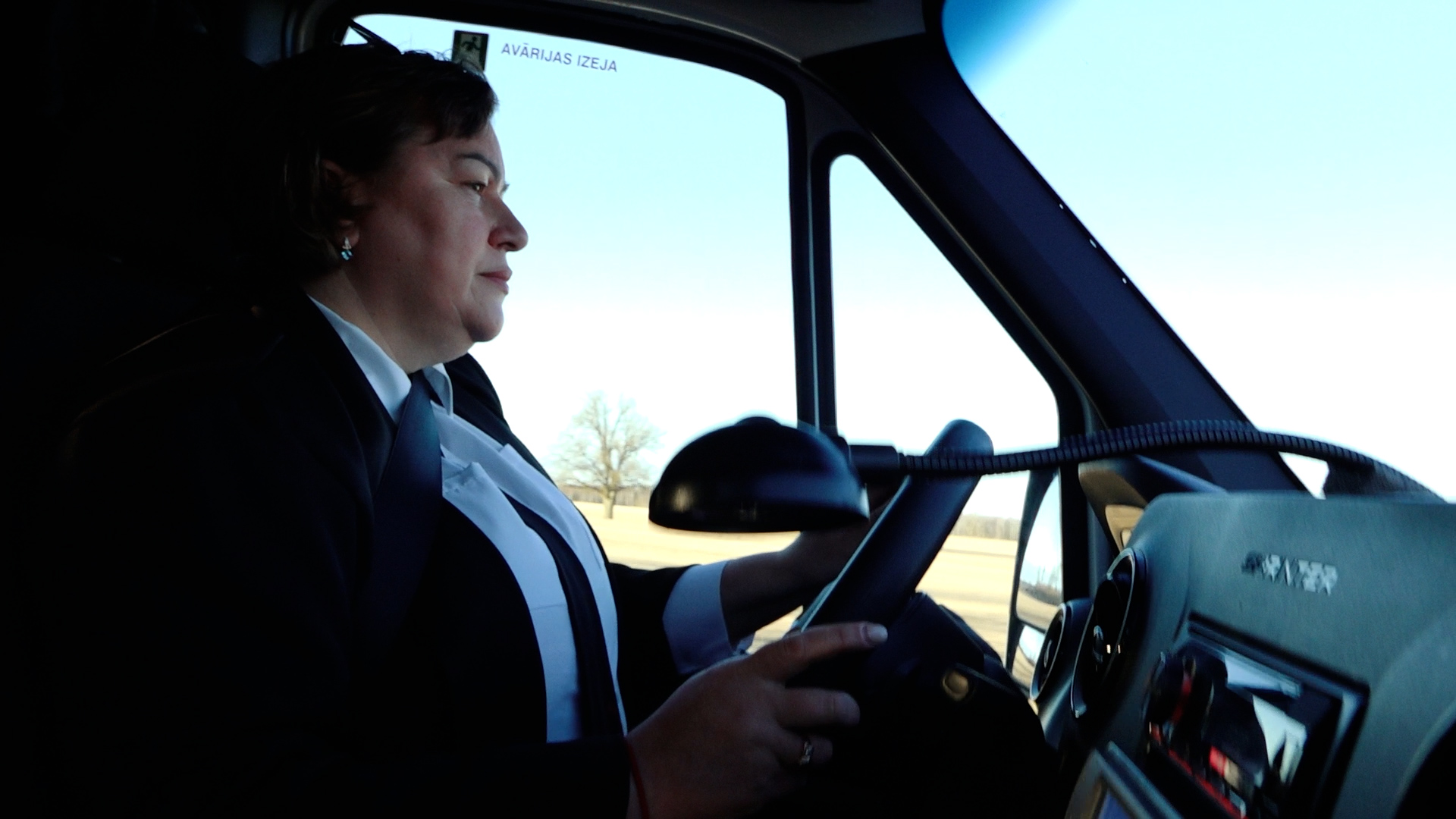 Sieviete pie autobusa stūres vada transportlīdzekli darba laikā.