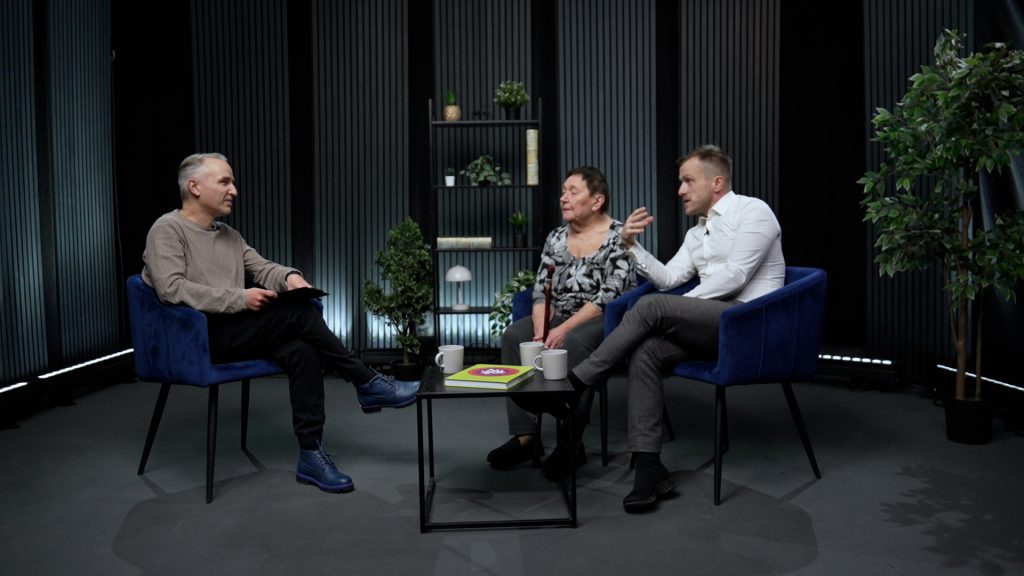 Atis Zviedris sarunājas ar Dailu Martinsoni un Kārli Būmeisteru televīzijas studijā, sēžot zilajos krēslos pie galdiņa